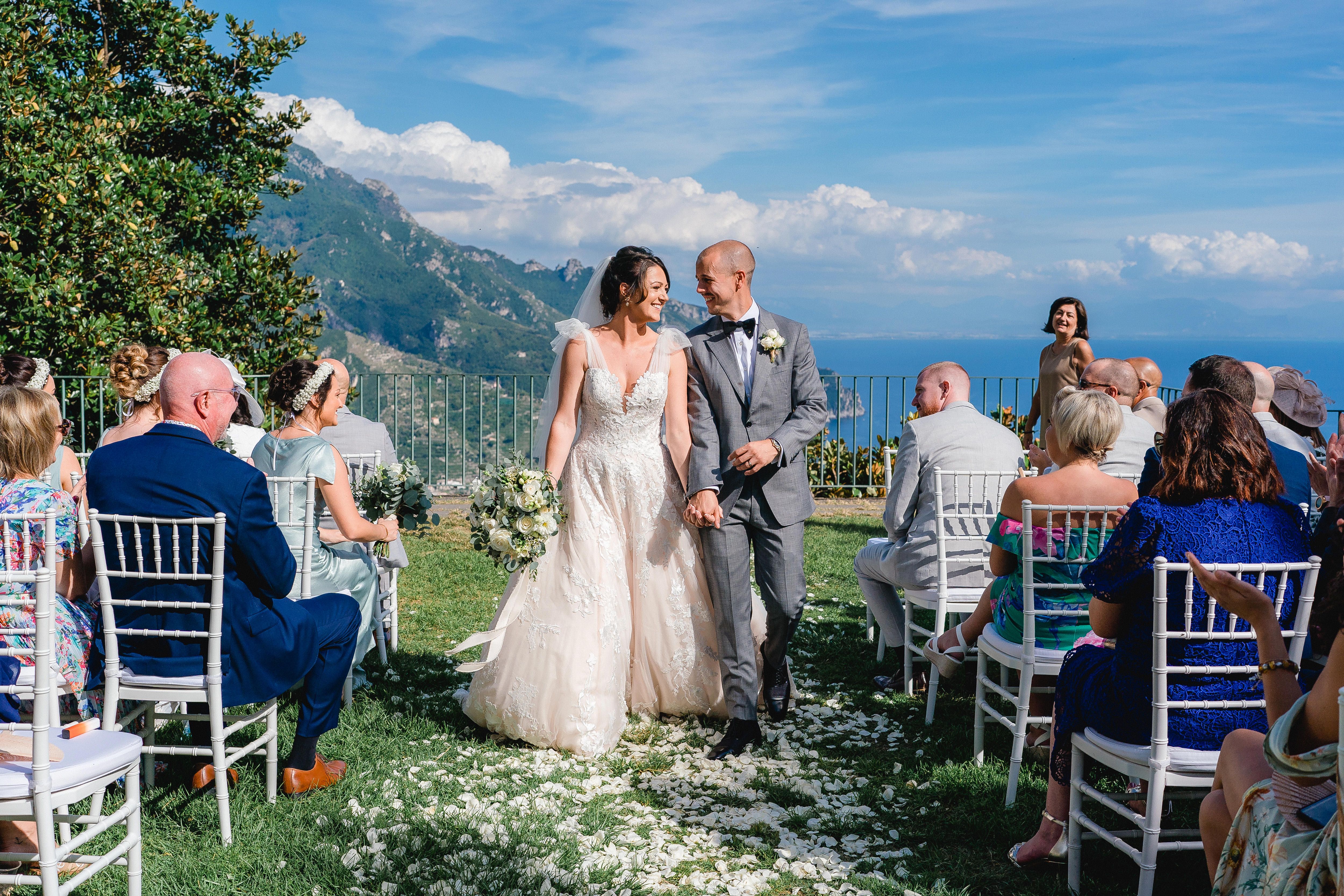 Brautpaar geht Hand in Hand durch den Trauungsgang, hoch über der Amalfiküste in Ravello